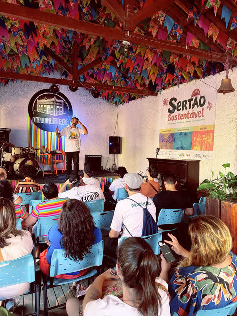 Apresentador no palco diante do público, sob as bandeirinhas