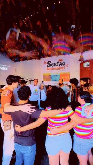 Grupo abraçado de costas, de frente para a faixa do festival