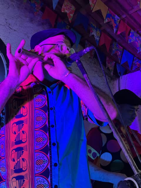 Músico tocando pífano com camisa colorida