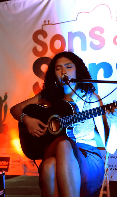 Cantora com violão no palco do Sons do Sertão