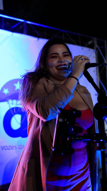 Cantora sorrindo ao microfone no Sons do Sertão