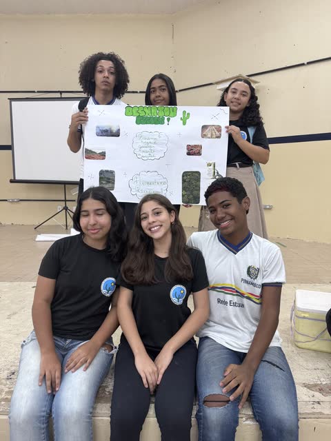 Estudantes sentados com o seu cartaz