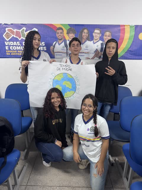 Estudantes com o cartaz Tempo de mudar
