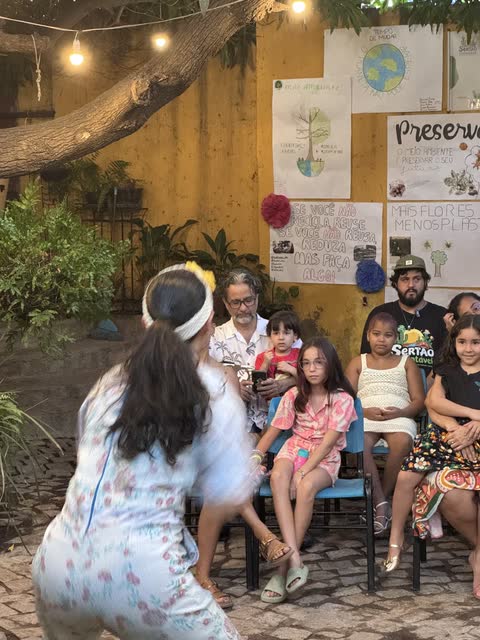 Atriz com maracá em cena para a plateia