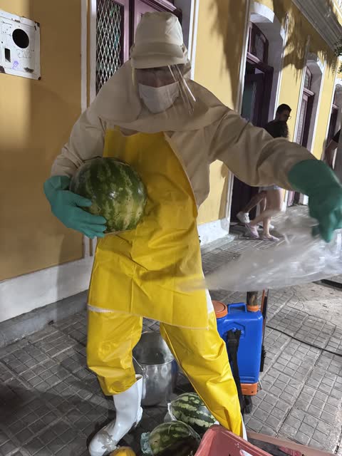 Performer de roupa de proteção amarela segurando uma melancia