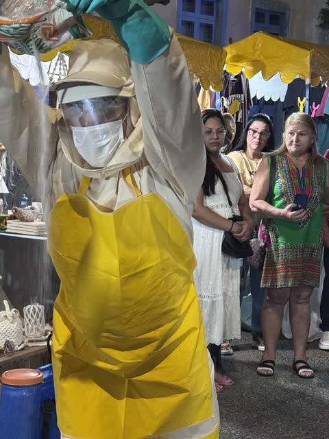 Performer de roupa de proteção com os braços erguidos diante do público