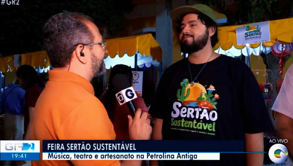 O produtor Noel, de camiseta preta do Sertão Sustentável, entrevistado ao vivo pela TV Grande Rio na feira